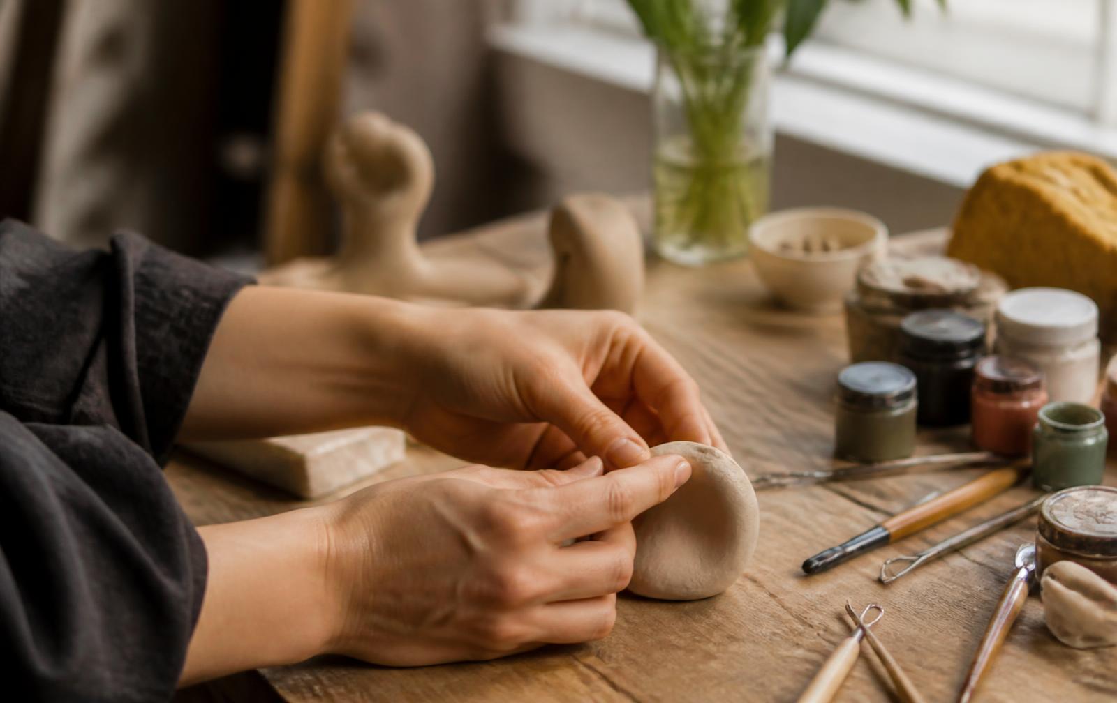 Handen aan het werk in het atelier met klei en gereedschap